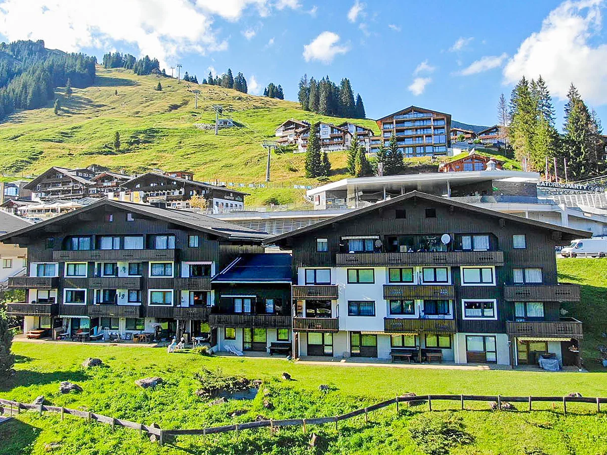 Apartmenthaus Haus am Anger in Königsleiten im Sommer, dahinter grüne Skihänge und Lift