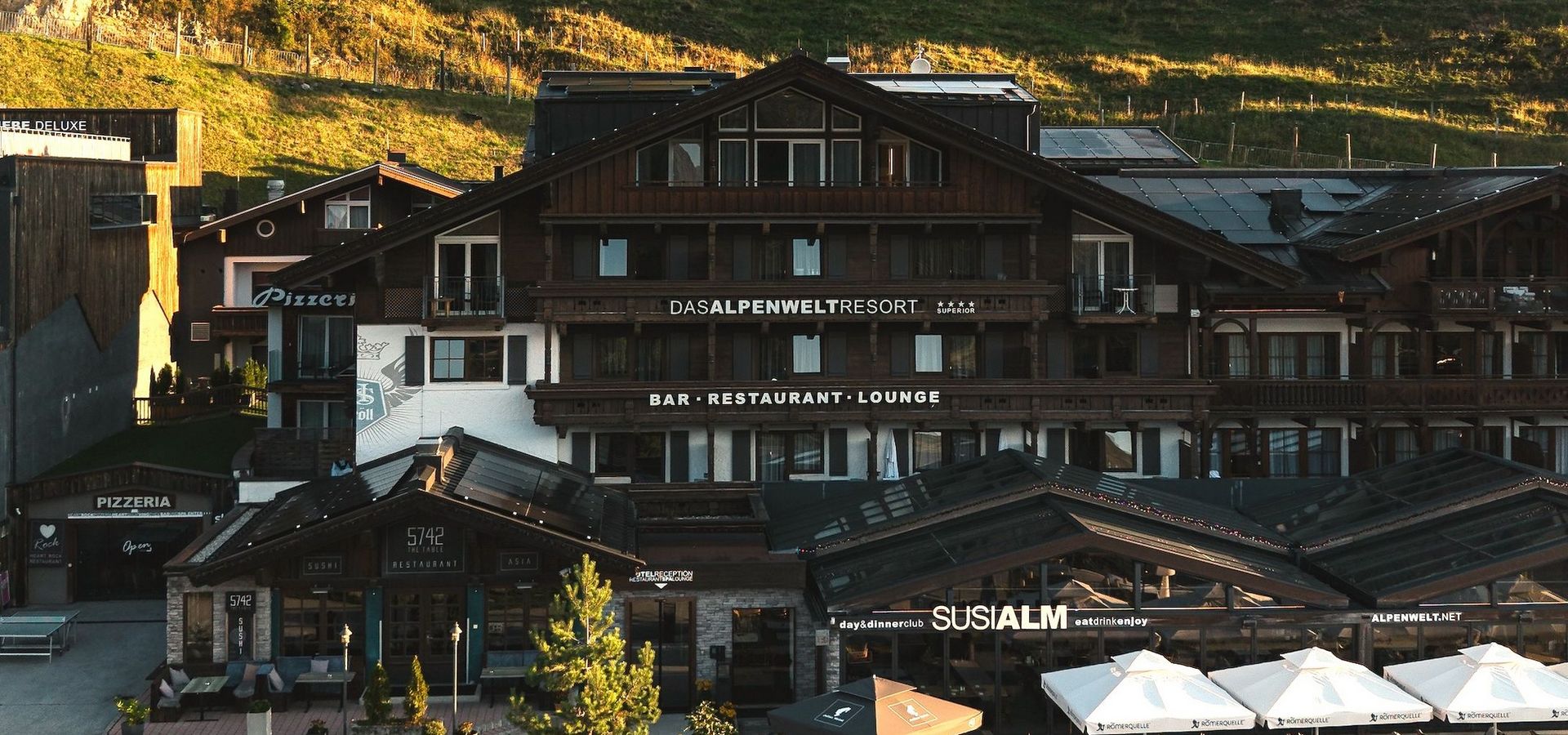 My Alpenwelt Resort mit Susi Alm, Restaurant-Terrasse und Sonnenschirmen in der Abendsonne